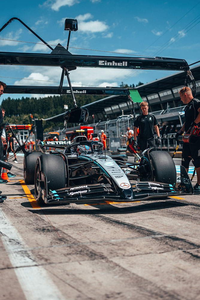Mercedes-AMG Formula 1 automobil je u pit stazi, okružen članovima tima ispod Einhell garažne konstrukcije.