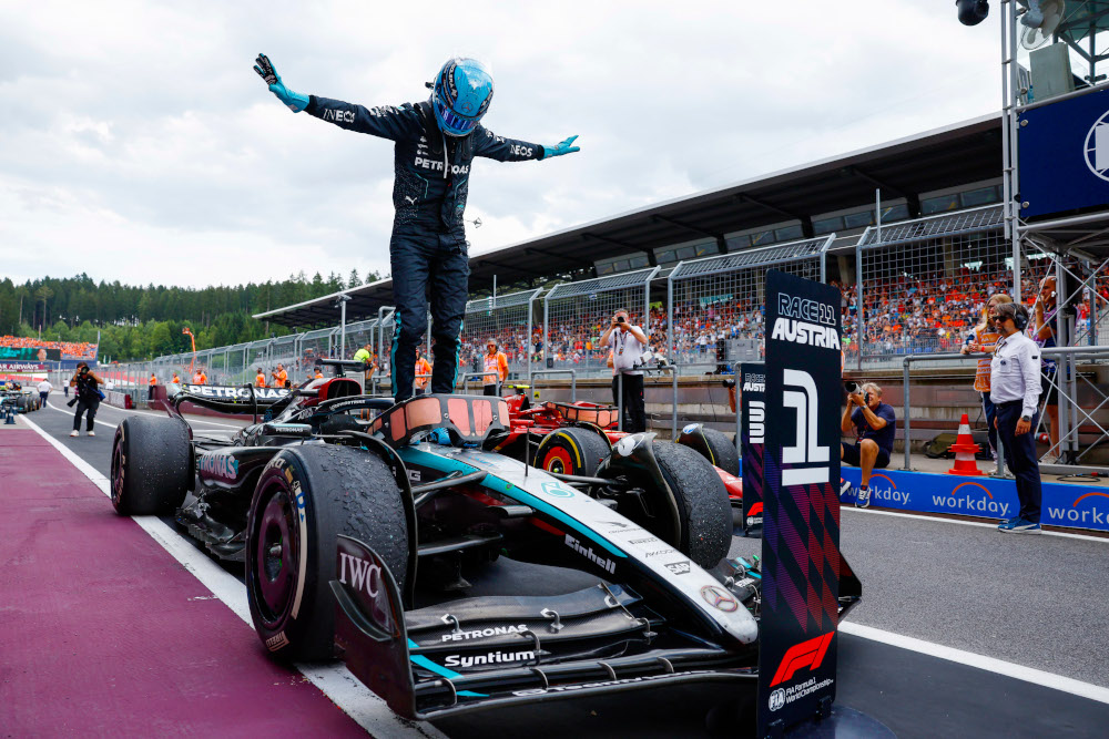 Formula 1 Mercedes racecar and the driver standing on it.