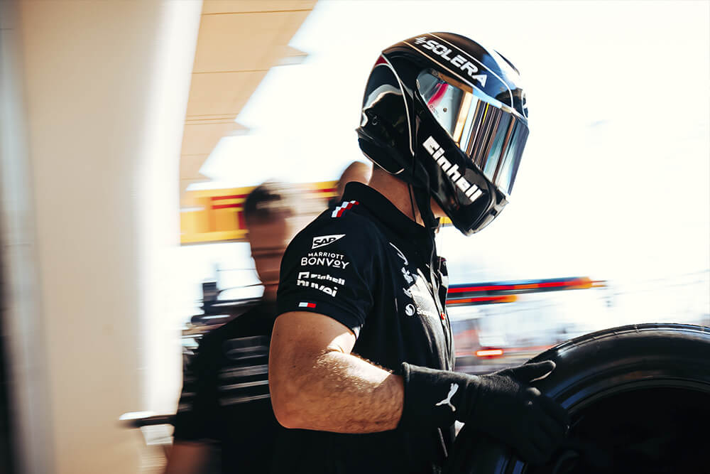 A formula 1 mercedes mechanic carrying a tyre